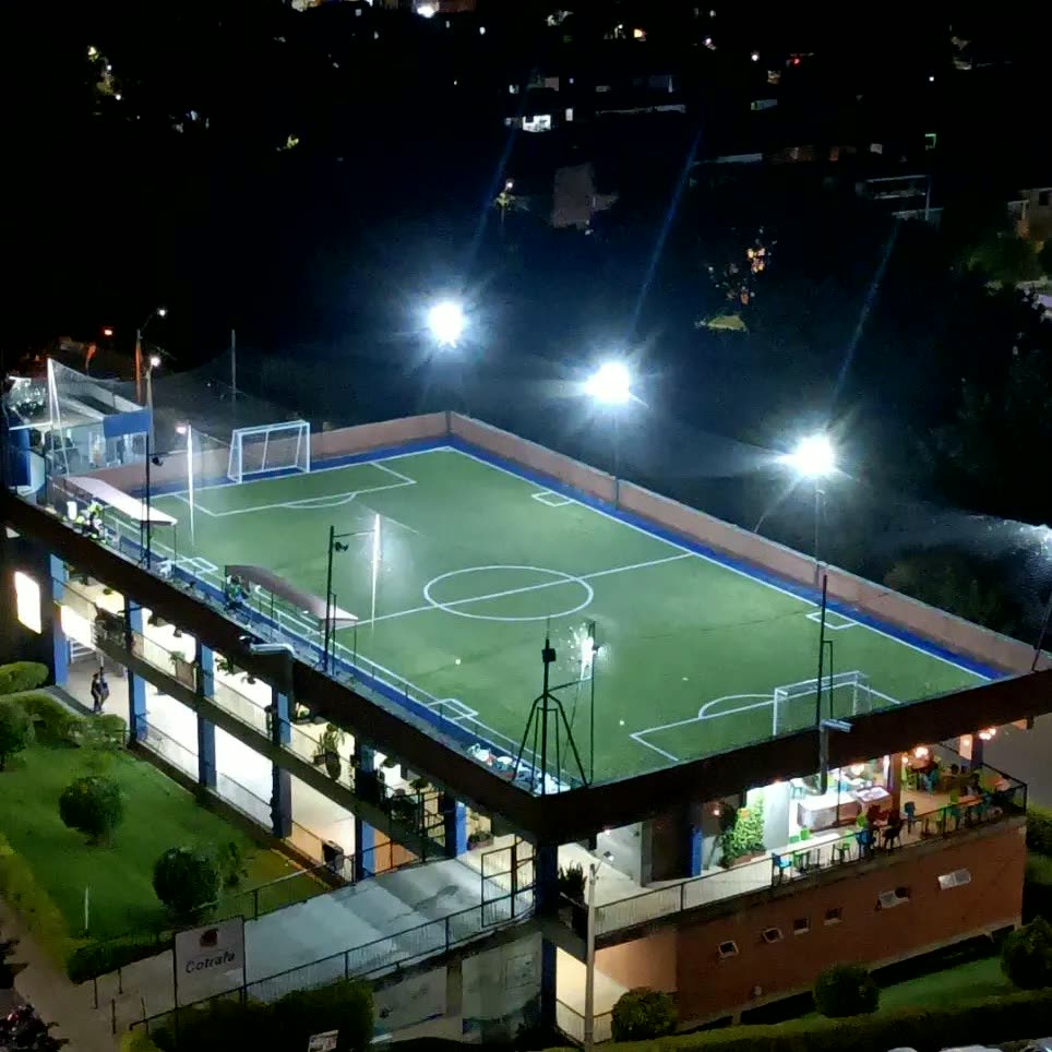 Sintética Paisajes de noche, vista desde arriba: la cancha en la terraza del edificio con los reflectores prendidos.